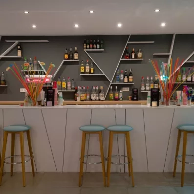 Un bar élégant avec des étagères exposant de nombreuses bouteilles.