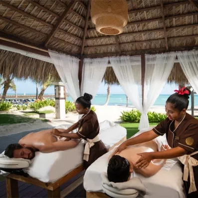 Deux personnes profitent d'un massage dans un pavillon extérieur, situé en bord de mer.