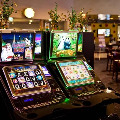 Une salle de casino présente plusieurs machines à sous électroniques.