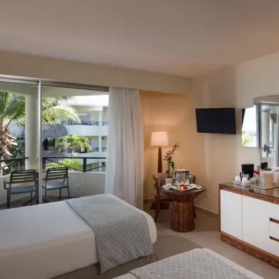 Une chambre avec un coin bureau, la télévision et une baie vitrée ouvrant sur une terrasse privée.