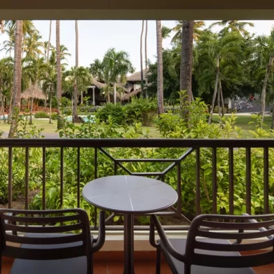 Un balcon avec une petite table et deux chaises, offrant une vue sur les jardins.