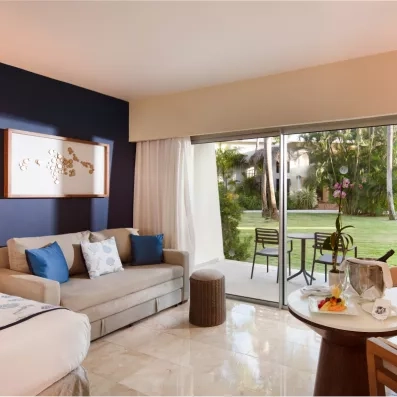 Une chambre moderne avec un canapé et une large baie vitrée ouvrant sur un jardin.