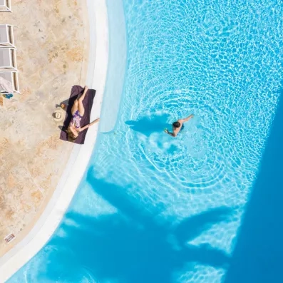Une vue aérienne montrant une personne nageant dans une piscine aux eaux turquoise.