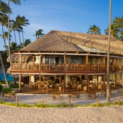 Un grand pavillon de plage, situé au bord de l'eau parmi les palmiers.