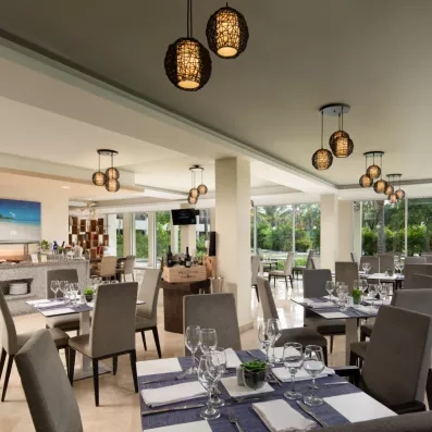 Une salle de restaurant moderne avec des tables dressées avec soin et des luminaires suspendus élégants.