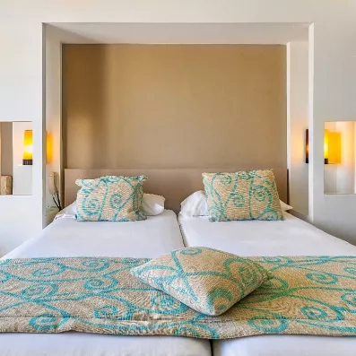 Détail de la literie confortable avec coussins aux motifs orientaux dans une chambre élégante du Palm Azur.