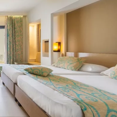 Suite lumineuse avec lits jumeaux et éclairage chaleureux offrant un cadre idéal pour vos vacances.