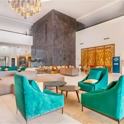 Lobby moderne de l'hôtel Palm Azur avec fauteuils turquoise, murs en marbre et design contemporain chic.