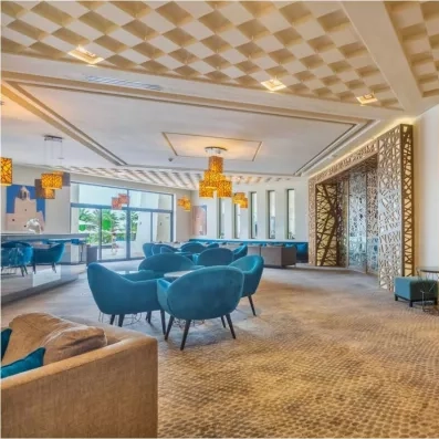 Salon de détente spacieux au Palm Azur doté de fauteuils bleus et d'un plafond à caissons décoratif.