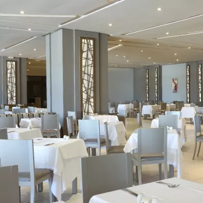 Salle de réception raffinée au Palm Azur avec tables nappées et éclairages muraux artistiques pour dîners.