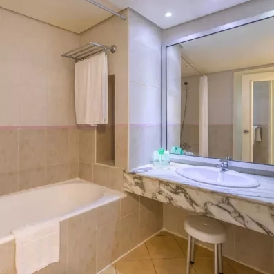 Salle de bain lumineuse avec baignoire et plan de toilette en marbre au Marhaba Salem Monastir.