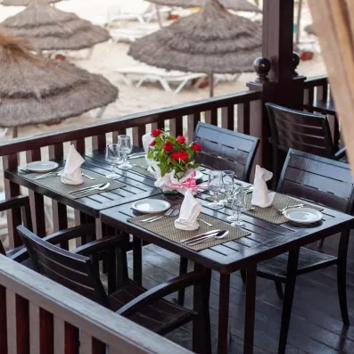 Table dressée sur une terrasse en bois avec vue sur la plage de l'hôtel Marhaba Salem.