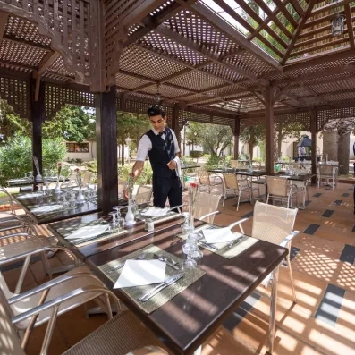 Terrasse ombragée sous une pergola en bois pour un déjeuner en plein air au Marhaba Salem.