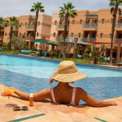 Une femme à la piscine de dos avec une vue sur les chambres de l'hôtel