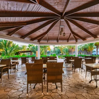 Terrasse ombragée sous une coupole en bois avec vue sur les jardins tropicaux de l'hôtel Djerba Resort.