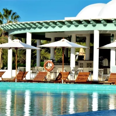 Piscine extérieure azur et terrasse avec transats sous les parasols au Royal Garden Palace en Tunisie.