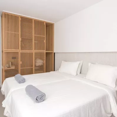 la chambre avec deux lits collés en blanc et une armoire de rangement en bois