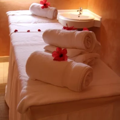 Table de massage de thalassothérapie avec serviettes blanches et fleurs d’hibiscus pour un séjour bien-être.