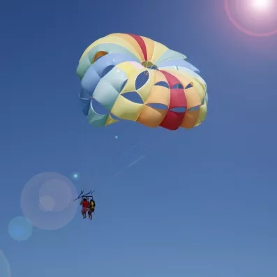 Activité de parachute ascensionnel multicolore dans le ciel bleu azur au-dessus de la mer à Djerba.