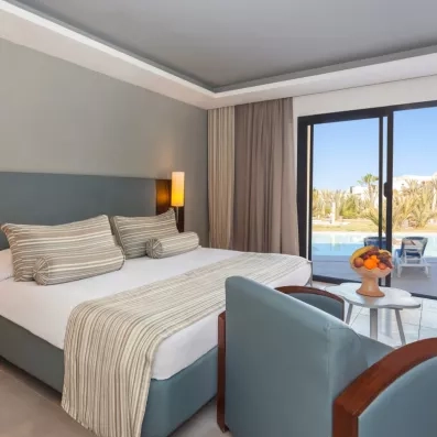 Chambre spacieuse de l'hôtel César Thalasso à Djerba avec vue imprenable sur la piscine et terrasse.