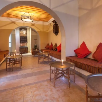 Salon de thé traditionnel tunisien avec banquettes colorées et tables en cuivre au César Thalasso Djerba.