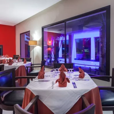 Table élégamment dressée avec serviettes en origami près d'une grande baie vitrée au César Thalasso.