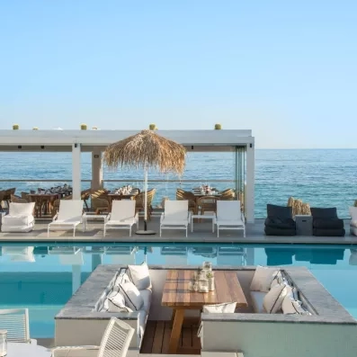 piscine extérieur avec une vue sur mer, transats  et salon du bar