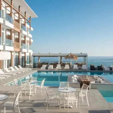 piscine extérieur avec une vue sur mer, transats  et salon du bar