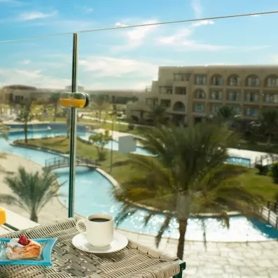 Vue sur piscine et jardins depuis une terrasse du Mövenpick Soma Bay, hôtel spa en bord de mer.