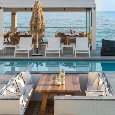 piscine extérieur avec une vue sur mer, transats  et salon du bar