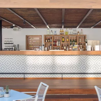 Le bar extérieur de l'hôtel avec comptoir décoré en bois, des tables et des chaises