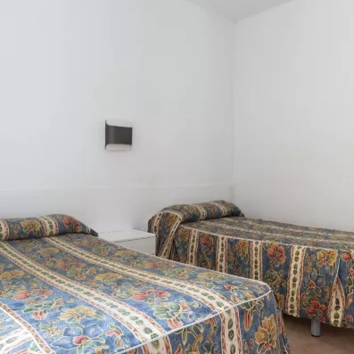 Une chambre disposant de deux lits simples recouverts de couvre-lits à motifs colorés.