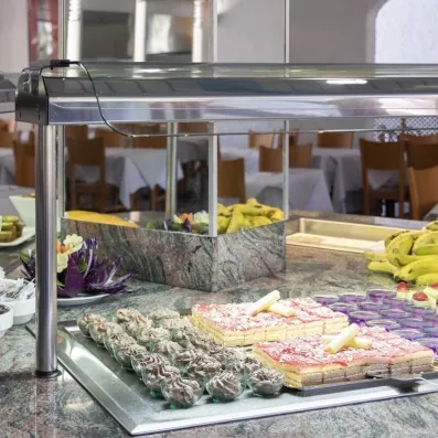 Un assortiment de pâtisseries et de desserts est exposé sur un comptoir réfrigéré.