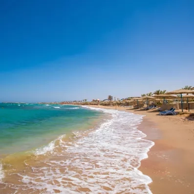 transats et parasols sur sable fin au bord de la plage 