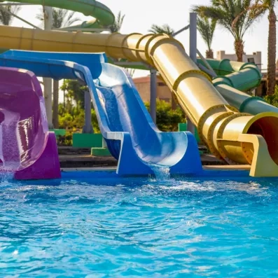 toboggans rose bleu et jaune versant de l'eau dans la piscine