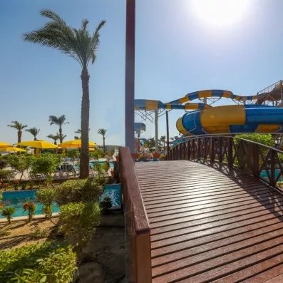 pont en bois menant aux toboggans traversant la piscine, palmiers, soleil