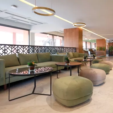 hall d'entrée décoré avec des chaises en rose, vert et gris et des tables basses et des plantes au milieu