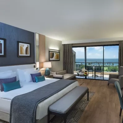 chambre avec un grand lit et un balcon vue sur la mer et le jardin