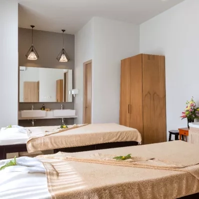 Une salle de soin comprenant deux tables de massage et un grand placard en bois.