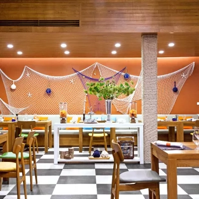 Une salle de restaurant décorée de filets de pêche, et d'un mobilier en bois chaleureux.