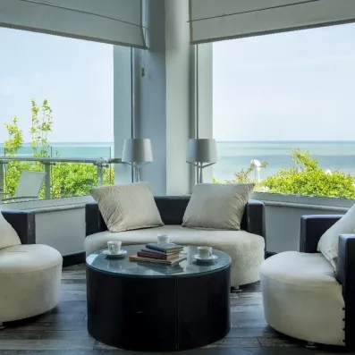 Un espace de détente intérieur offrant une vue sur la mer grâce à des baies vitrées.