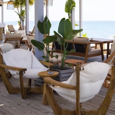 Un salon d'extérieur avec des fauteuils en bois et une végétation tropicale.