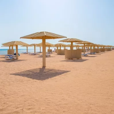 Plage de sable fin et parasols en bois au Premier Le Rêve Hôtel & Spa, Hurghada Égypte.