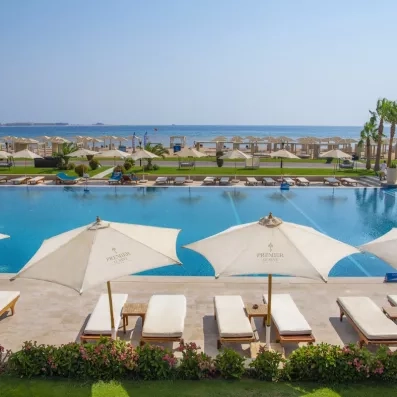 Transats avec parasols bordant une piscine face à la mer, séjour luxe à Hurghada, Égypte.