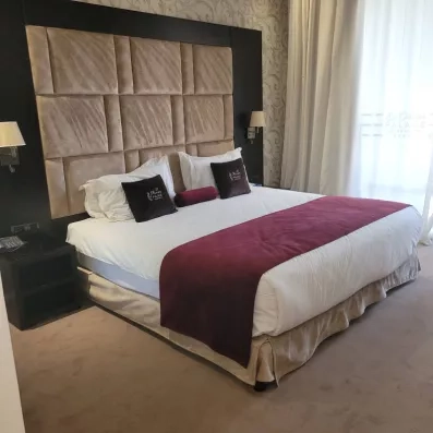 lit double lit double avec une tête de lit en tissu et en bois marron et juste à côté une fenêtre 