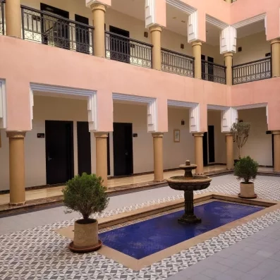 patio des chambres donnant sur une fontaine et un bassin entourée de faillances oreintale