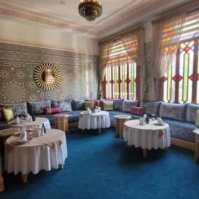 café maure de l'hôtel avec petites tables rondes et un mur décoré avec du carrelage orientale