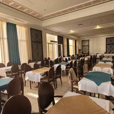 restaurant de l'hôtel avec tables et chaises avec des accoudoirs, juste en face des baies vitrés 