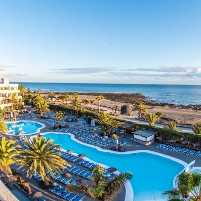 Une vaste piscine bordée de transats, avec l'océan à perte de vue en arrière-plan.