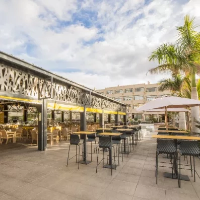 Une terrasse extérieure ombragée par une structure métallique.